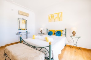 A bedroom with a bed, a bedside table, a mirror, and artwork on the wall.