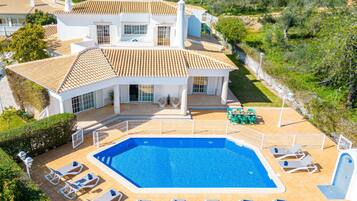 A large house with a swimming pool and multiple sun loungers.