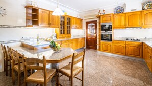 A kitchen with wooden cabinets, a granite countertop, and a dining area with wooden chairs.