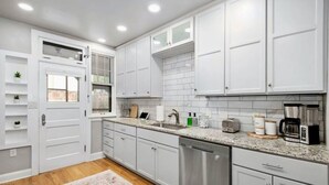 A modern kitchen with white cabinets, a dishwasher, a coffee maker, and a toaster. - Dundee's 3BR Upscale Retreat, Near Downtown! (Omaha)
