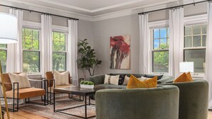 A living room with a green sofa set, a coffee table, and a painting on the wall. - Dundee's 3BR Upscale Retreat, Near Downtown! (Omaha)