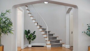 A staircase with white railings and wooden steps leading to a landing. - Dundee's 3BR Upscale Retreat, Near Downtown! (Omaha)
