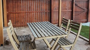 An outdoor patio with a wooden table and chairs, a ceiling fan, and a wooden fence in the background. - Cantina Stagecoach Stop (Grants)