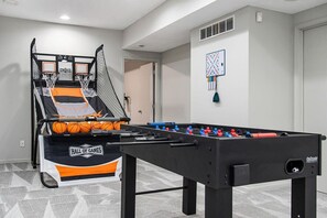 A room with a foosball table and a basketball hoop.