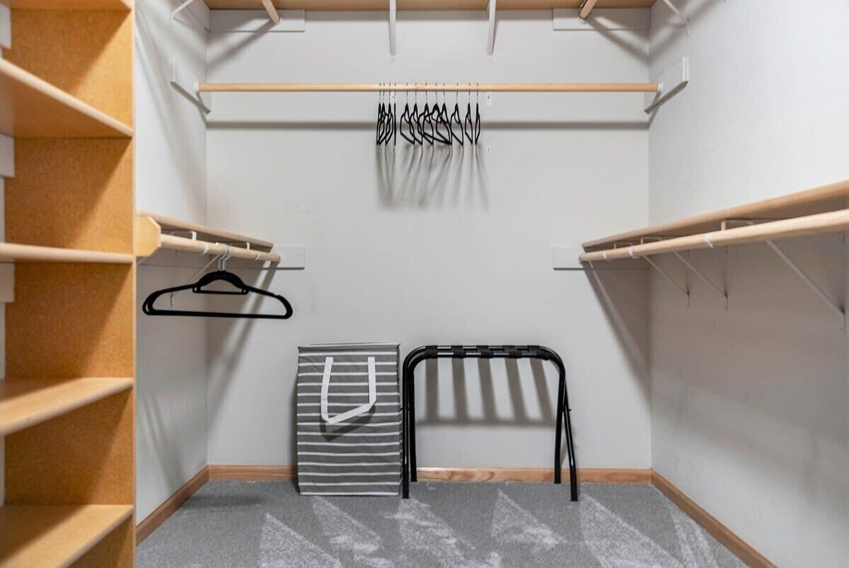 Un closet amplio con estantes de madera, una barra para colgar ropa y un zapatero.