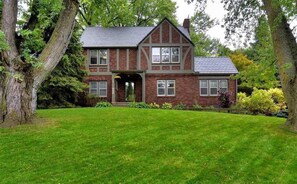 A two-story brick house with a gabled roof, a front entrance, and a well-maintained lawn.