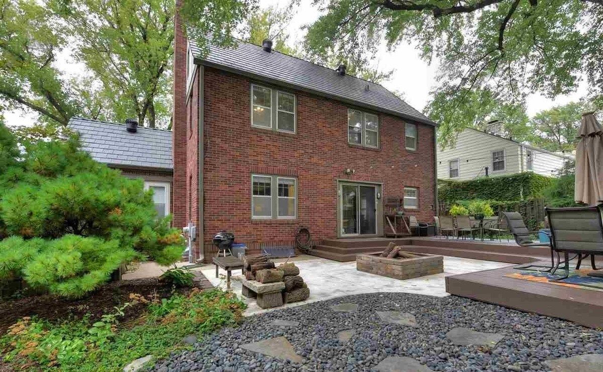A brick house with a patio area, outdoor seating, and a fire pit.