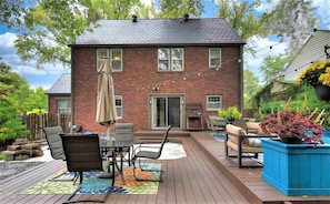 A brick house with a deck, outdoor furniture, and a garden.
