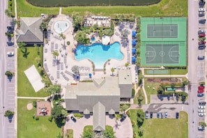 Eine Vogelperspektive auf einen Resort mit Schwimmbad, Tennisplätzen und Parkplatz.