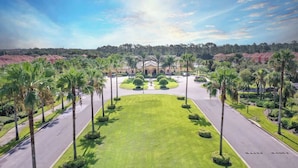 A well-maintained road with palm trees and a central building, surrounded by greenery. - 5 BR Villa+Pool&Lake views+Near Disney+WaterPark (Kissimmee)