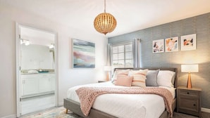 A bedroom with a bed, bedside tables, a hanging light fixture, a window with curtains, and a wall with framed pictures. - 5 BR Villa+Pool&Lake views+Near Disney+WaterPark (Kissimmee)