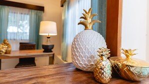 A wooden table with decorative items including a white textured vase and two golden pineapple-shaped containers.