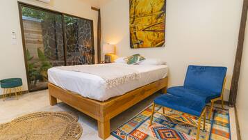 A bedroom with a wooden bed, a blue chair, a patterned rug, and a large painting on the wall.
