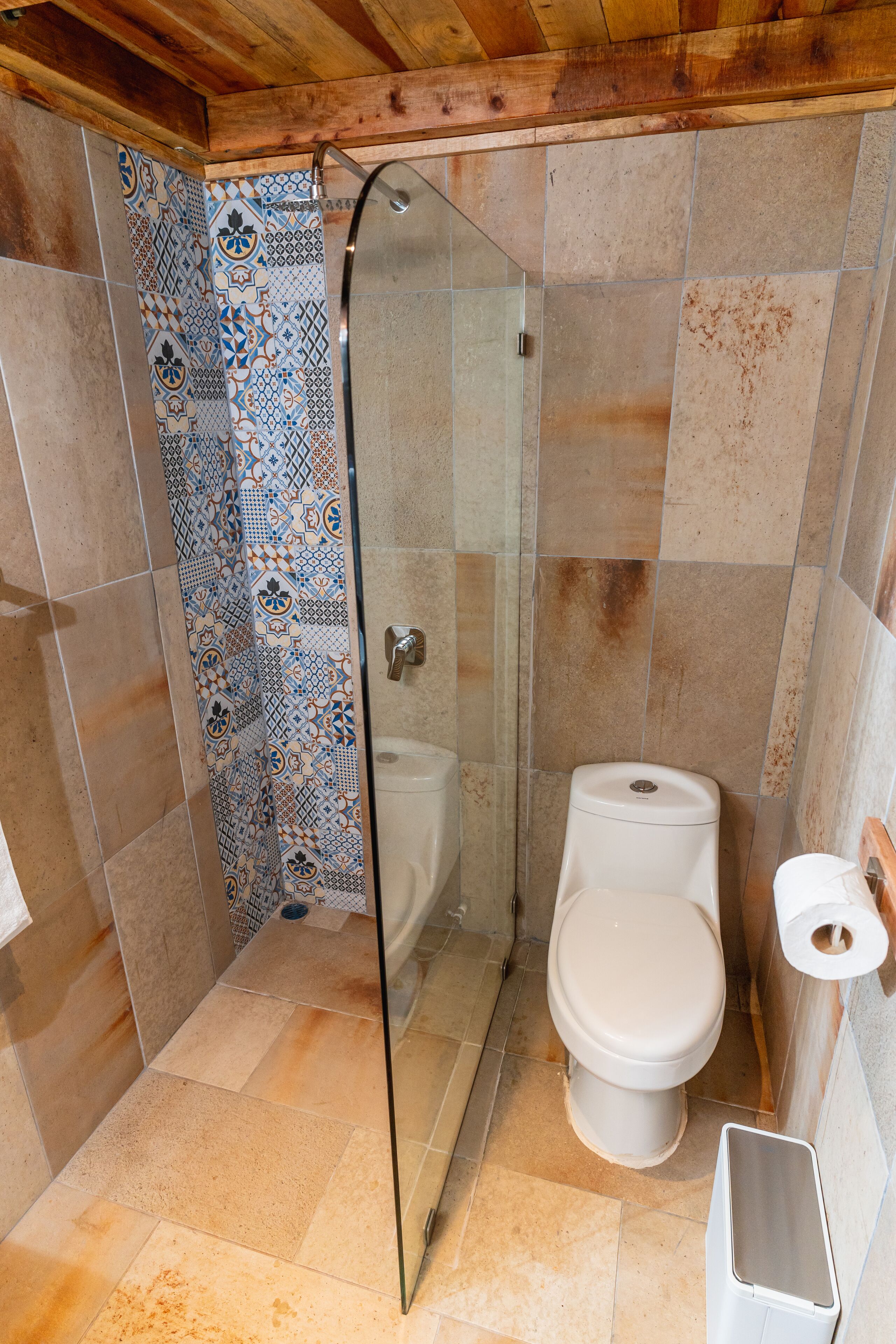 A bathroom with a shower, toilet, and a trash bin.