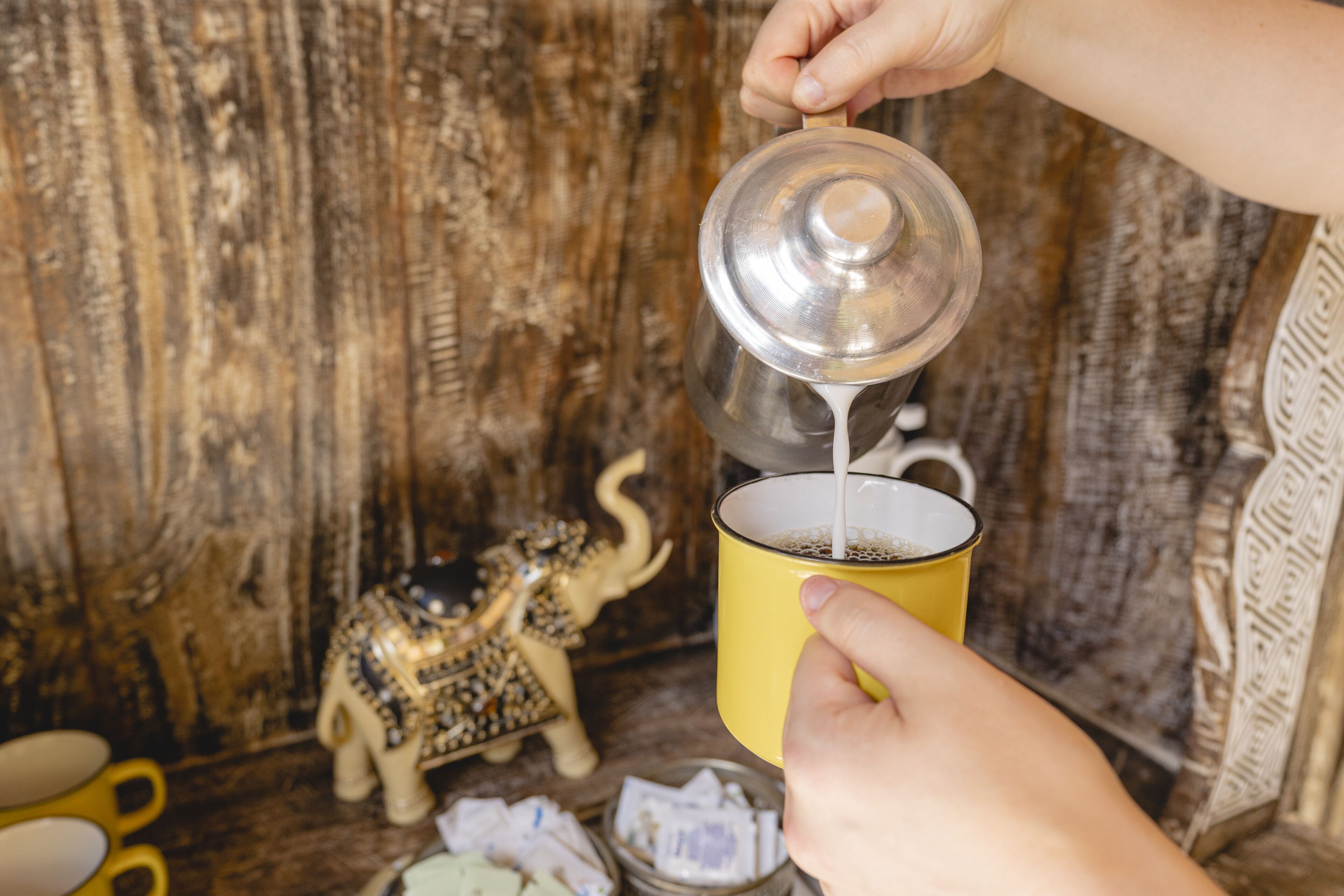 A person pouring coffee into a yellow mug.