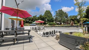 Outdoor seating with umbrellas, a chessboard, and a Coca-Cola sign. - Wren's Nest Manorcombe 41 (Gunnislake)