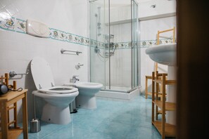 Un baño con dos inodoros, una ducha y un lavabo.