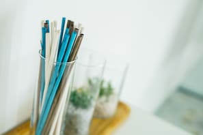 A clear glass container holding several pencils with blue and brown colors. - Archi Bianchi  (Cefalù)