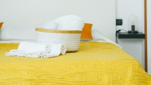 A bed with a yellow bedspread, a white towel, and a woven basket. - Archi Bianchi  (Cefalù)