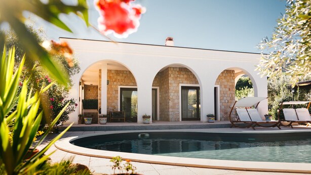 A modern house with a pool, featuring three arched doorways and a stone facade. - Archi Bianchi  (Cefalù)