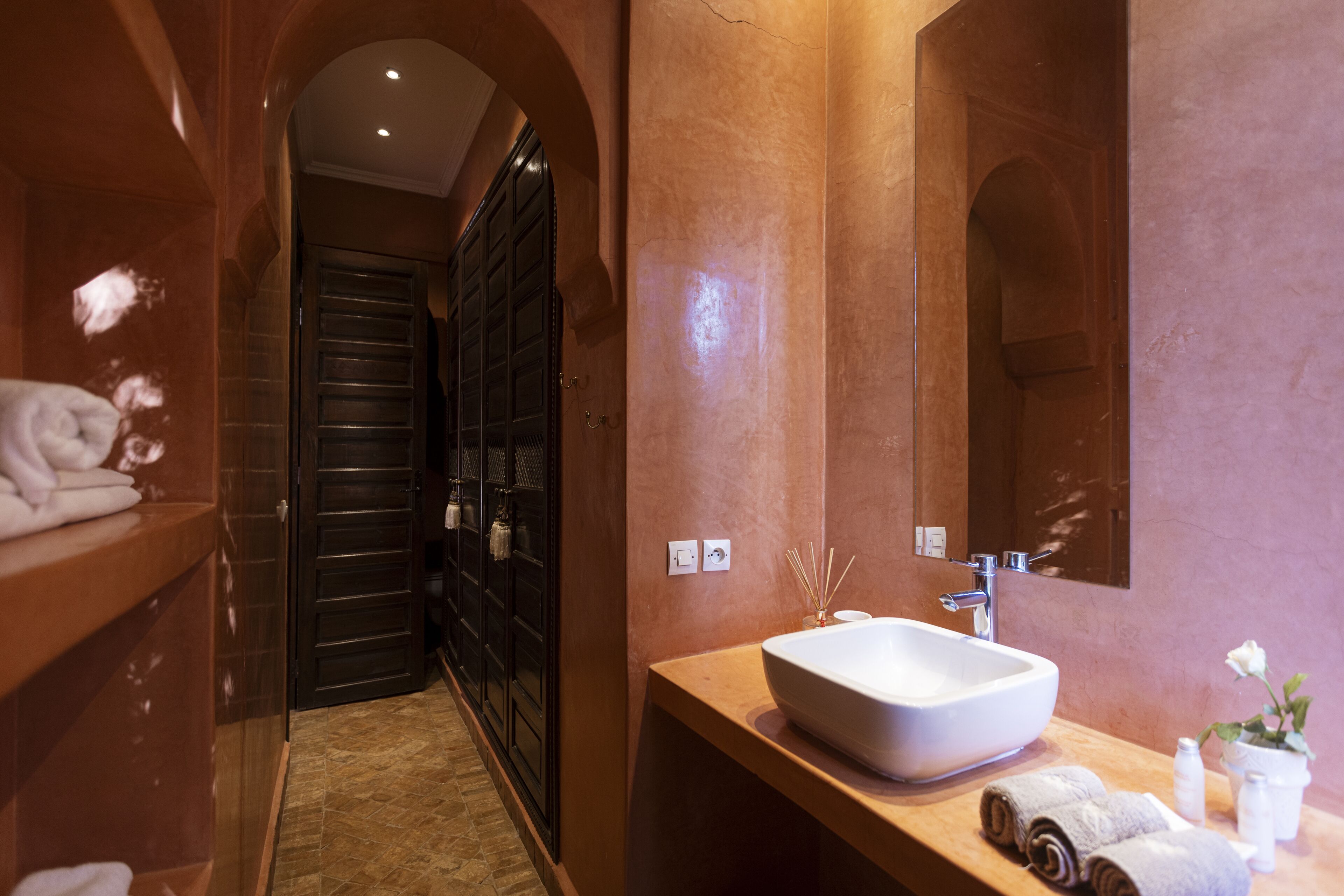 A modern bathroom with a large mirror, a white sink, and a towel rack.