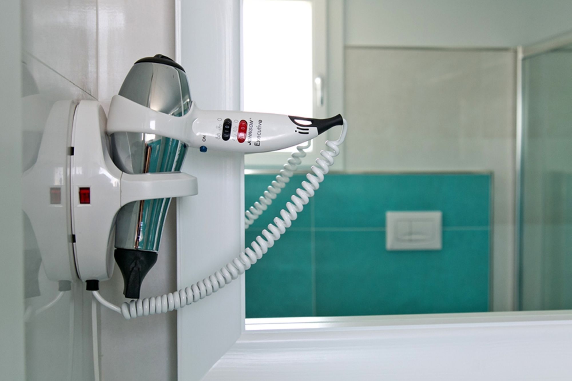 Un sèche-cheveux fixé au mur, avec un cordon enroulé.