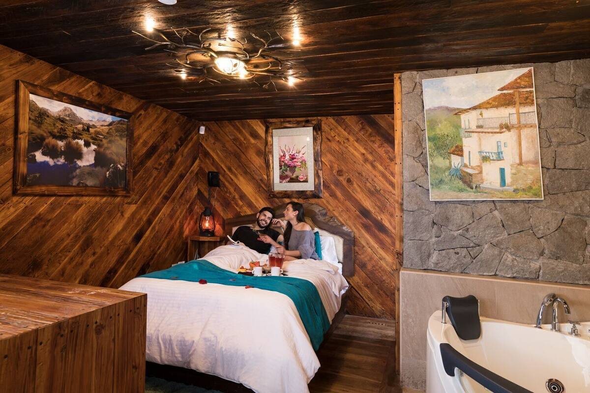 Une pièce chaleureuse avec un lit, un plafond en bois, un mur en pierre et un tableau.