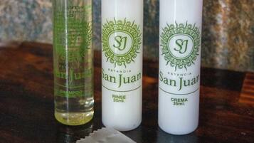 Tres botellas de productos para el cuidado del cabello San Juan sobre una superficie de madera.