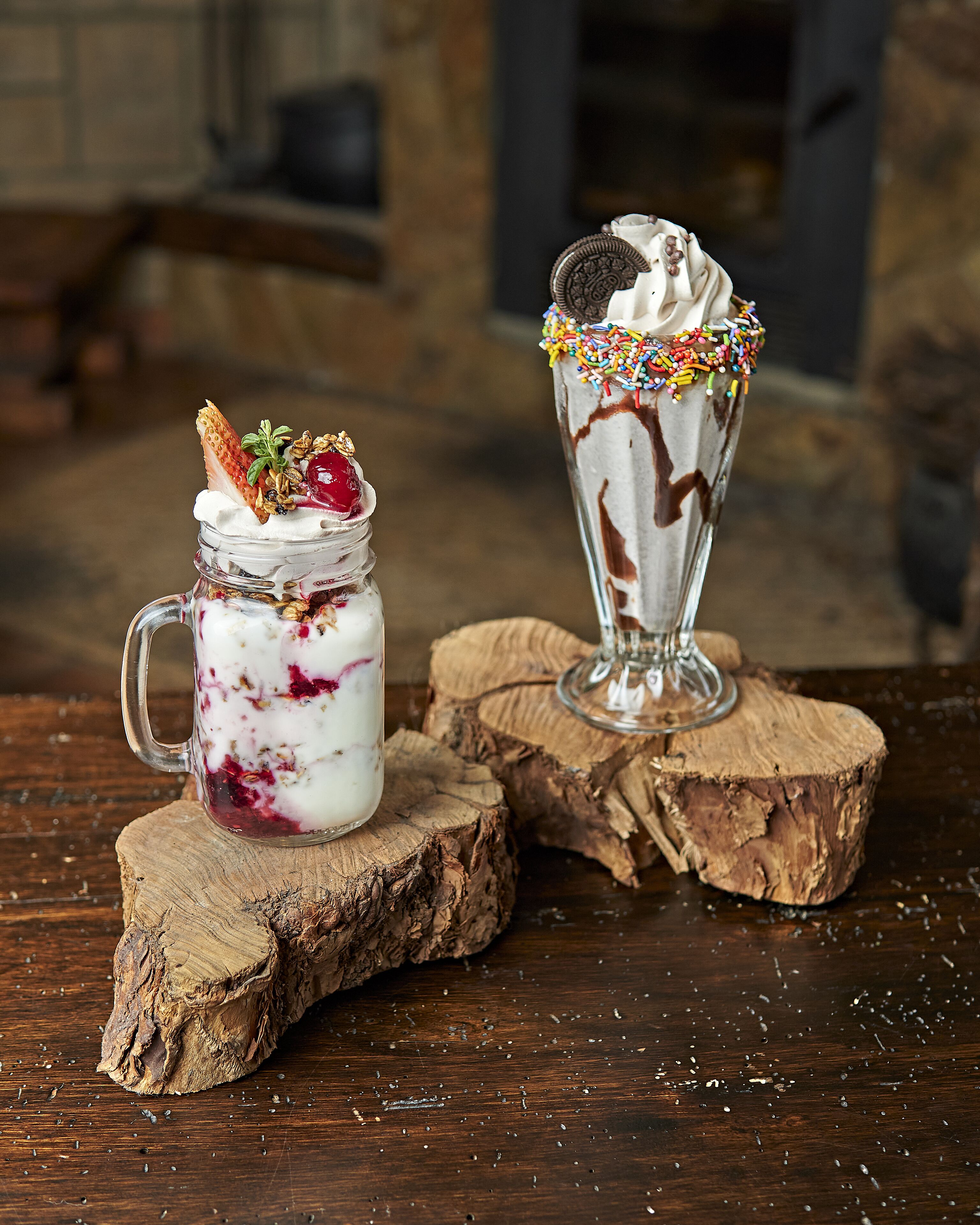Two dessert drinks on wooden coasters.