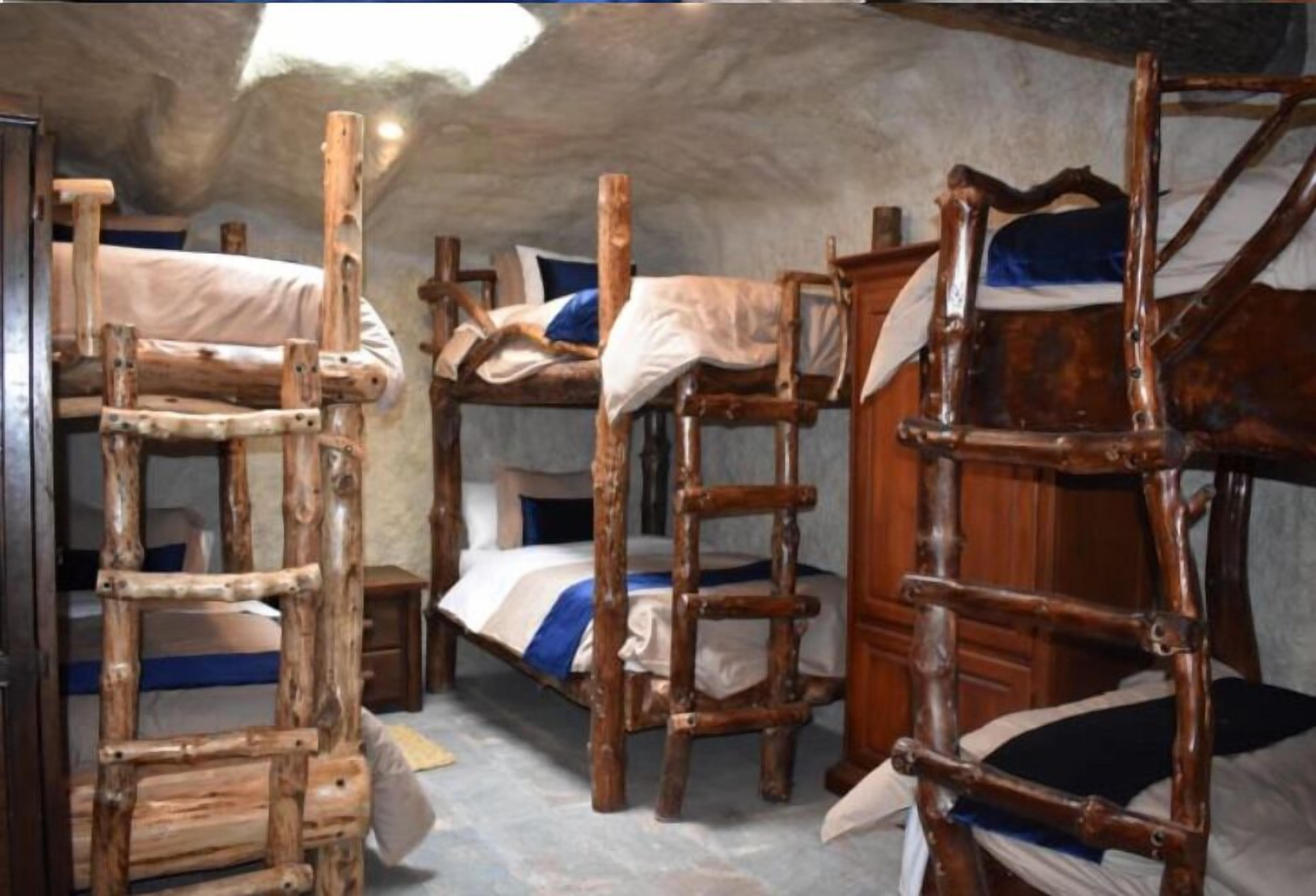 A rustic room with bunk beds and wooden ladders.