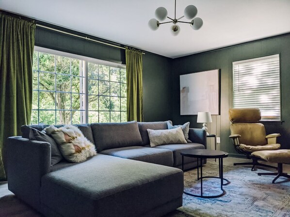 A living room with a sectional sofa, a small table, a chair, and a lamp.