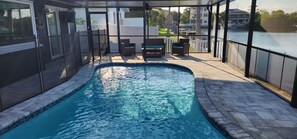 An indoor swimming pool with a glass enclosure, seating area, and a view of a body of water. - Double Waterfront Property with Amazing Views & Private Pool (Hernando Beach)