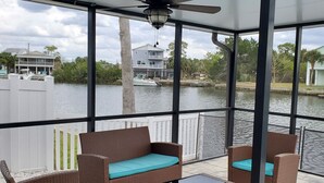A covered outdoor seating area with wicker furniture and a view of a body of water and buildings. - Double Waterfront Property with Amazing Views & Private Pool (Hernando Beach)