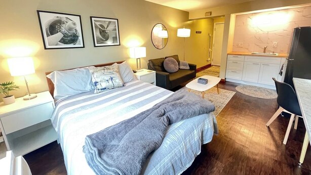 Een hotelkamer met een bed, een bank, een kleine tafel, een spiegel en een kitchenette.