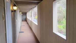 A corridor with wooden walls, large windows, and a light fixture.