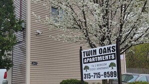 A sign for Twin Oaks Apartments, indicating 1 & 2 bedroom studio apartments, with a contact number.