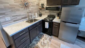 A modern kitchen with a granite countertop, stainless steel appliances, and dark cabinetry.