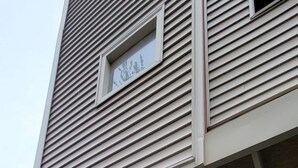 Un immeuble à la façade beige, un escalier beige menant à un palier, et une boîte aux lettres avec les numéros 7 à 13.