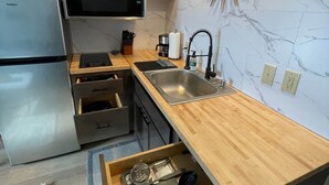 Une cuisine moderne avec un dosseret en marbre, un four encastré, un évier et un plan de travail en bois.