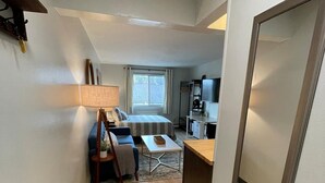 Un couloir étroit mène à une chambre qui contient un lit, un bureau et une chaise.