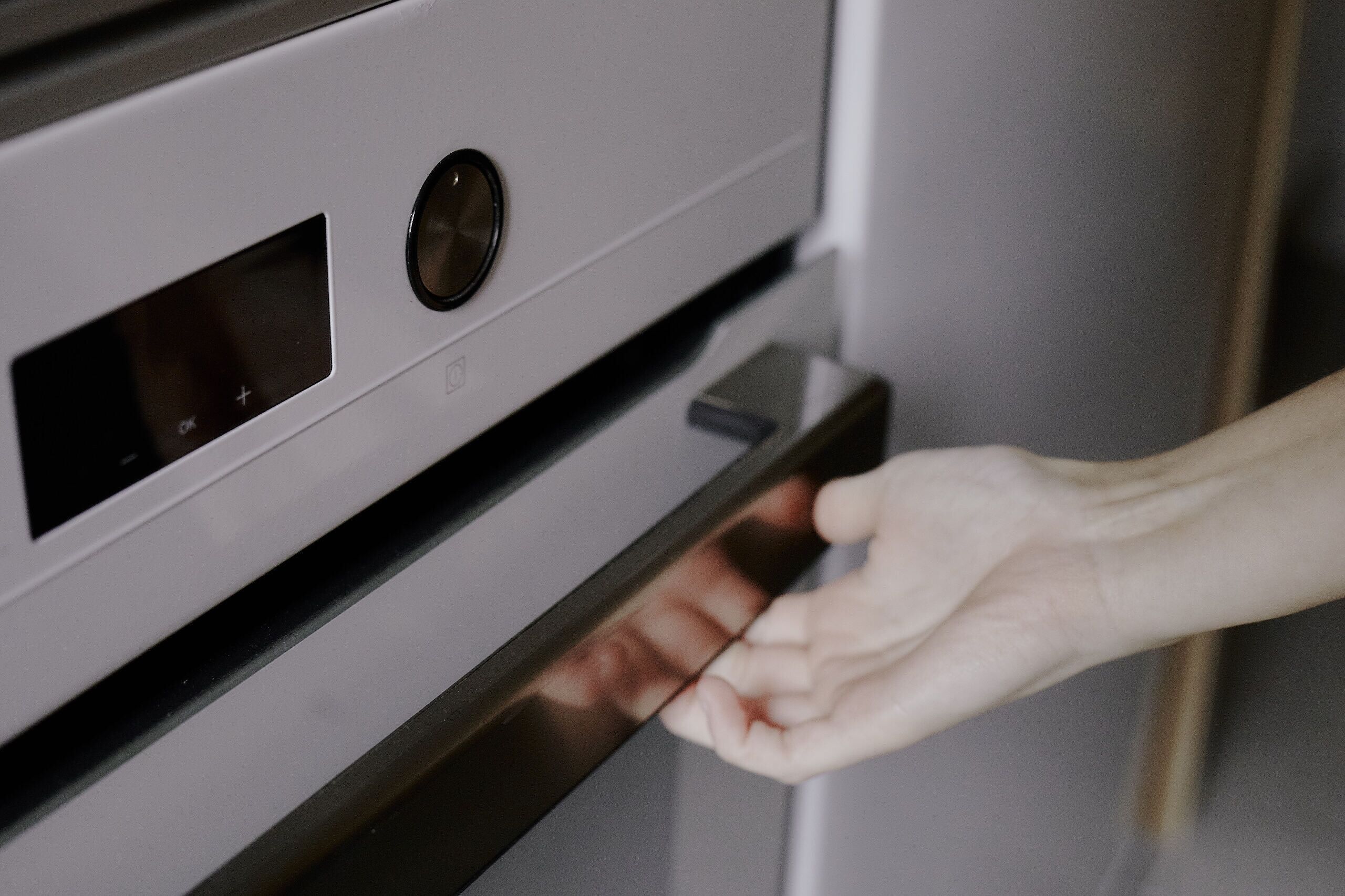 A hand opening a stainless steel oven door.