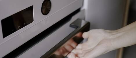 A hand opening a stainless steel oven door.
