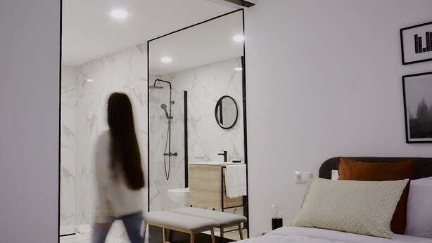 A modern hotel room with a large bed, a wooden headboard, a bedside table, and a mirror. - ZAREY HOSTEL (Oleiros)
