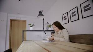 A person sitting at a wooden table with a lamp, surrounded by framed motivational quotes on the wall. - ZAREY HOSTEL (Oleiros)