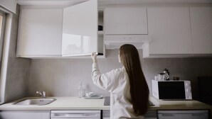A modern kitchen with white cabinets, a stainless steel sink, and a microwave. - ZAREY HOSTEL (Oleiros)