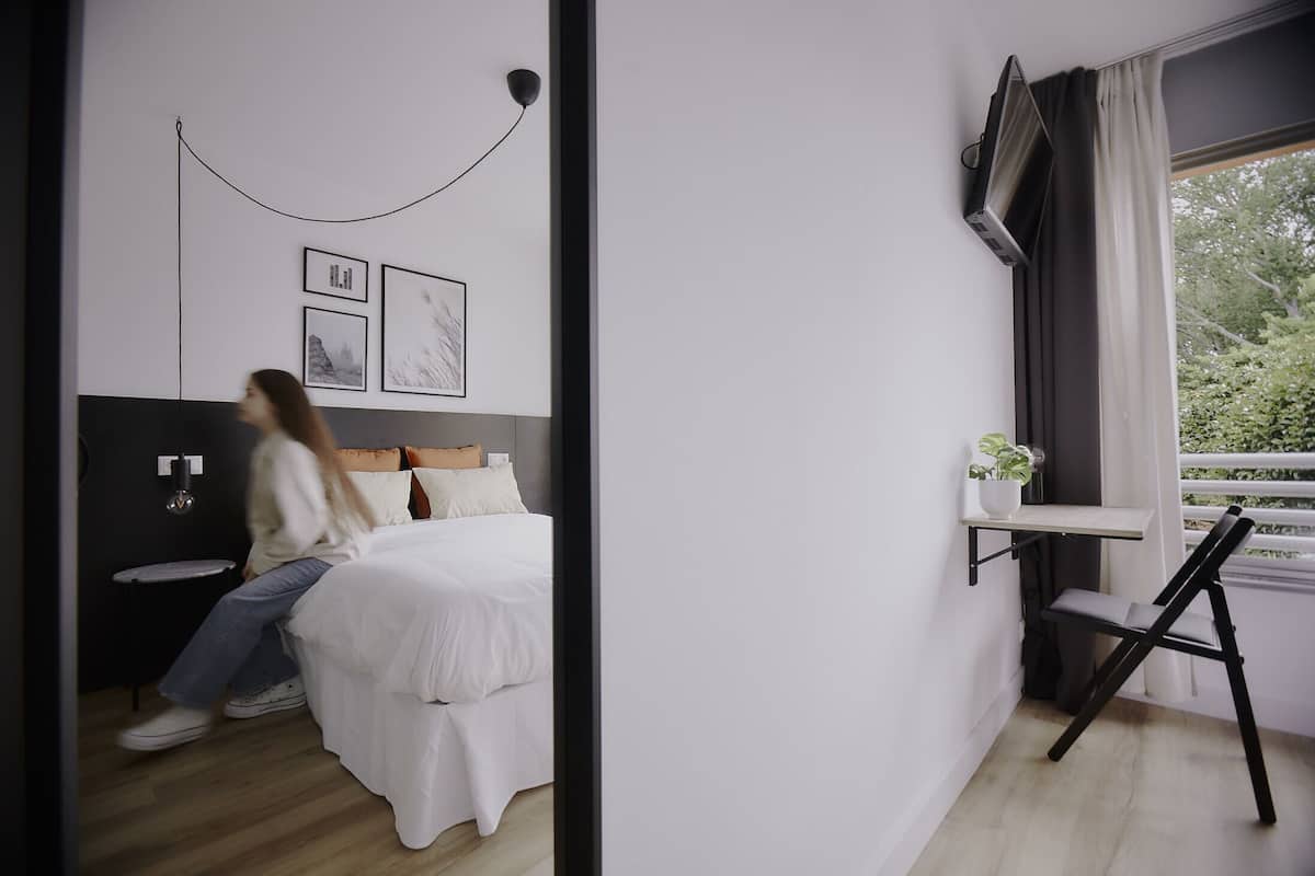 Une chambre à coucher moderne avec un lit, une table de chevet et une fenêtre avec des rideaux.