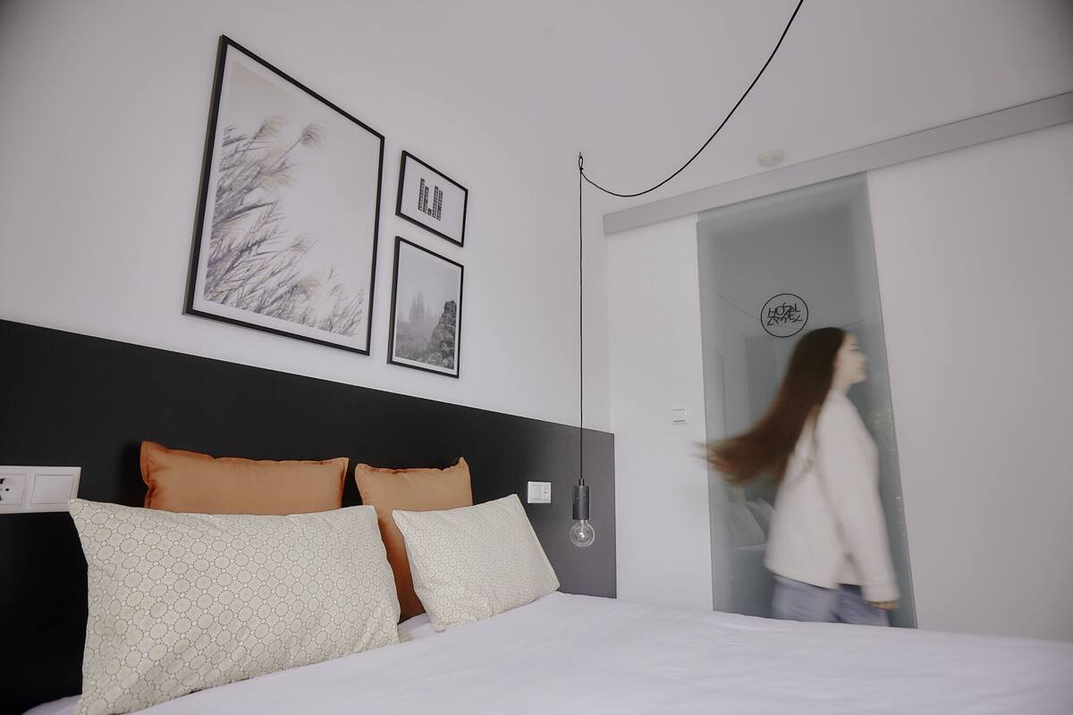 Une chambre à coucher moderne avec un lit, une table de chevet et un luminaire fixé au mur.