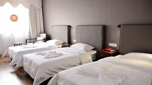 A hotel room with three single beds, a small table, and a chair. - Luguhu Aishang Hotel (Ninglang)