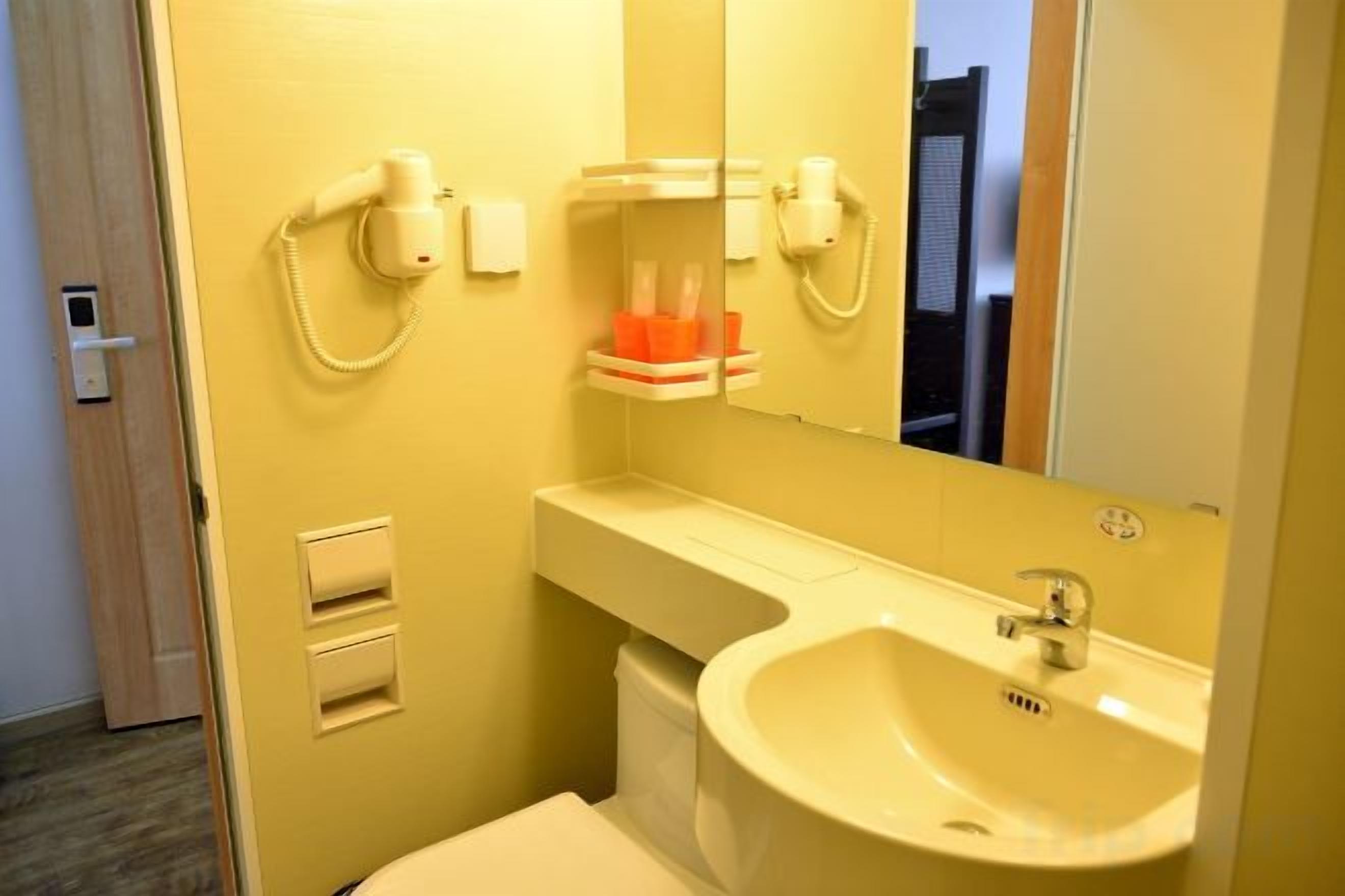 Ein Badezimmer mit Waschbecken, Spiegel, Handtuchhalter und Toilette.