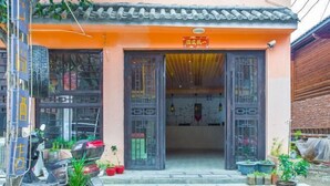 A building with a traditional tiled roof and a sign above the entrance. - Luguhu Aishang Hotel (Ninglang)